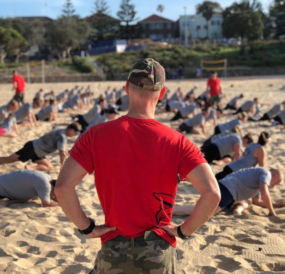 Original Bootcamp coach overseeing a group training session on the beach